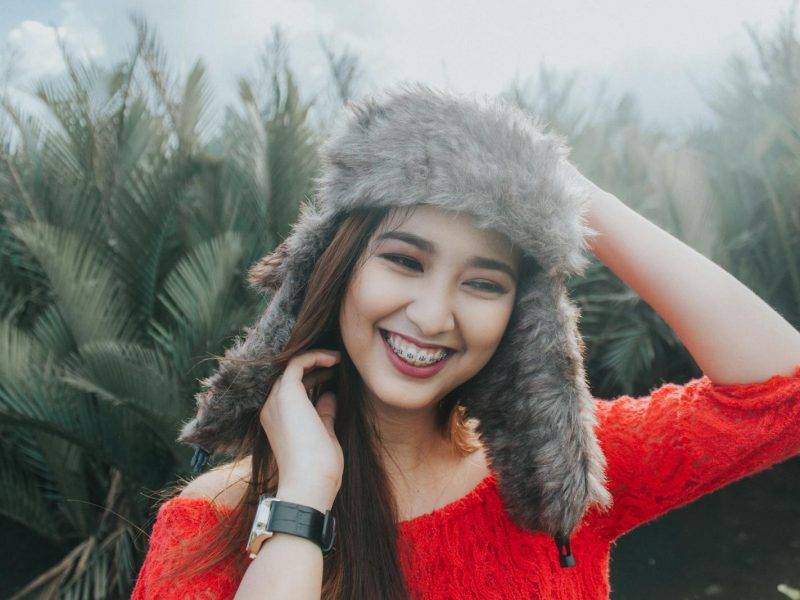 Woman In Red Off Shoulder Top Wearing Fur Beanie Smiling for Photo