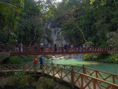 a group of people walking across a bridge over a river