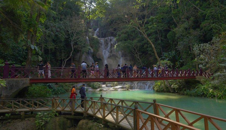 a group of people walking across a bridge over a river