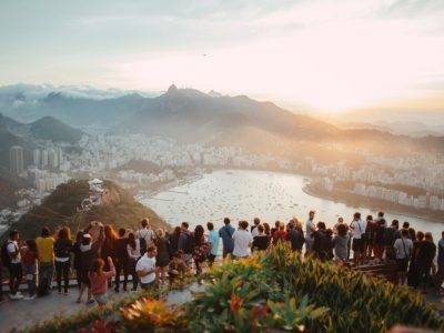 group of people standing facing lake view