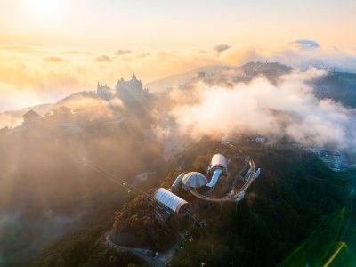 A breathtaking aerial shot of the mist-covered Ba Na Hills with cable cars in Vietnam at sunrise.